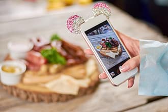 Woman taking a photo of grilled sausages Woman hand using smartphone to take a photo of dish Woman taking a photo of delicious food with smartphone at restaurant